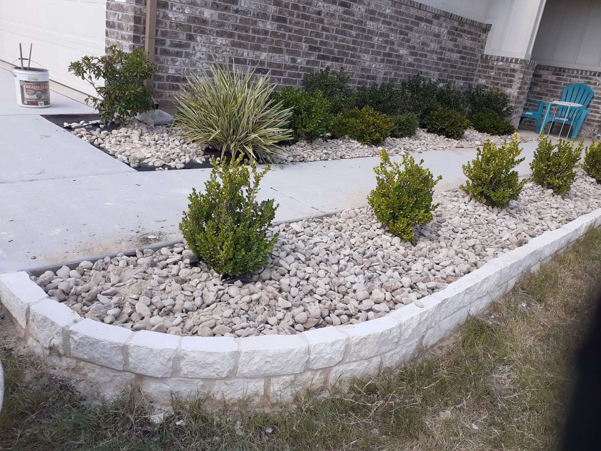 Landscaped front yard with white stone edging and shrubs — Ancfence LLC